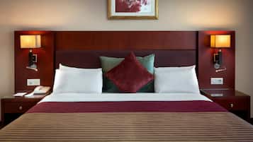 A hotel room with a large bed, two bedside tables, a nightstand, a telephone, and two wall-mounted lamps.