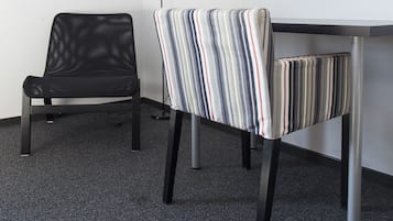 Een moderne kamer met een zwarte lederen fauteuil, een gestreepte stoel en een bureau met een flatscreentelevisie aan de muur.