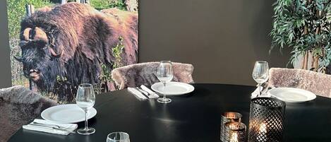 A dining table set for four with candles, plates, and cutlery.