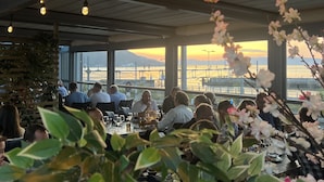 A restaurant with a view of a bridge and sunset. Tables are set with glasses and plates. - P-Hotels Brattøra (Trondheim)