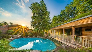 A wooden cabin with a pool, surrounded by lush greenery and a deck. - Maximus Resort (Brno)