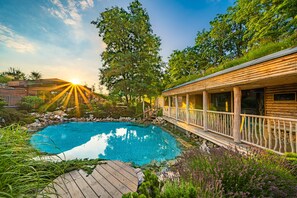 Eine Holzdiele mit Pool, umgeben von üppiger Vegetation und einer Terrasse.