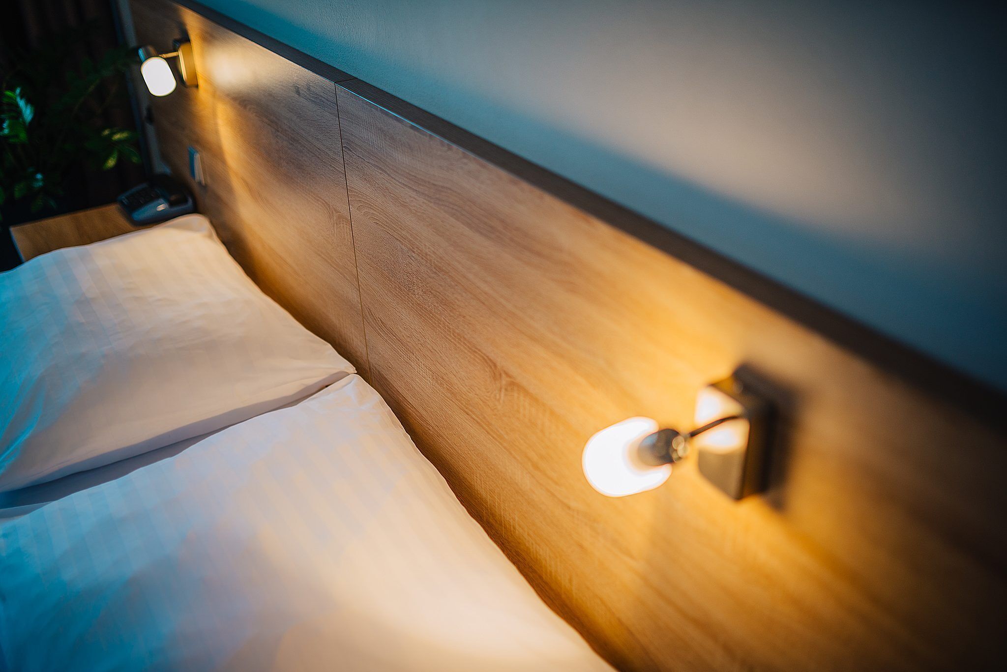 Cama bem arrumada com cabeceira de madeira e abajur.