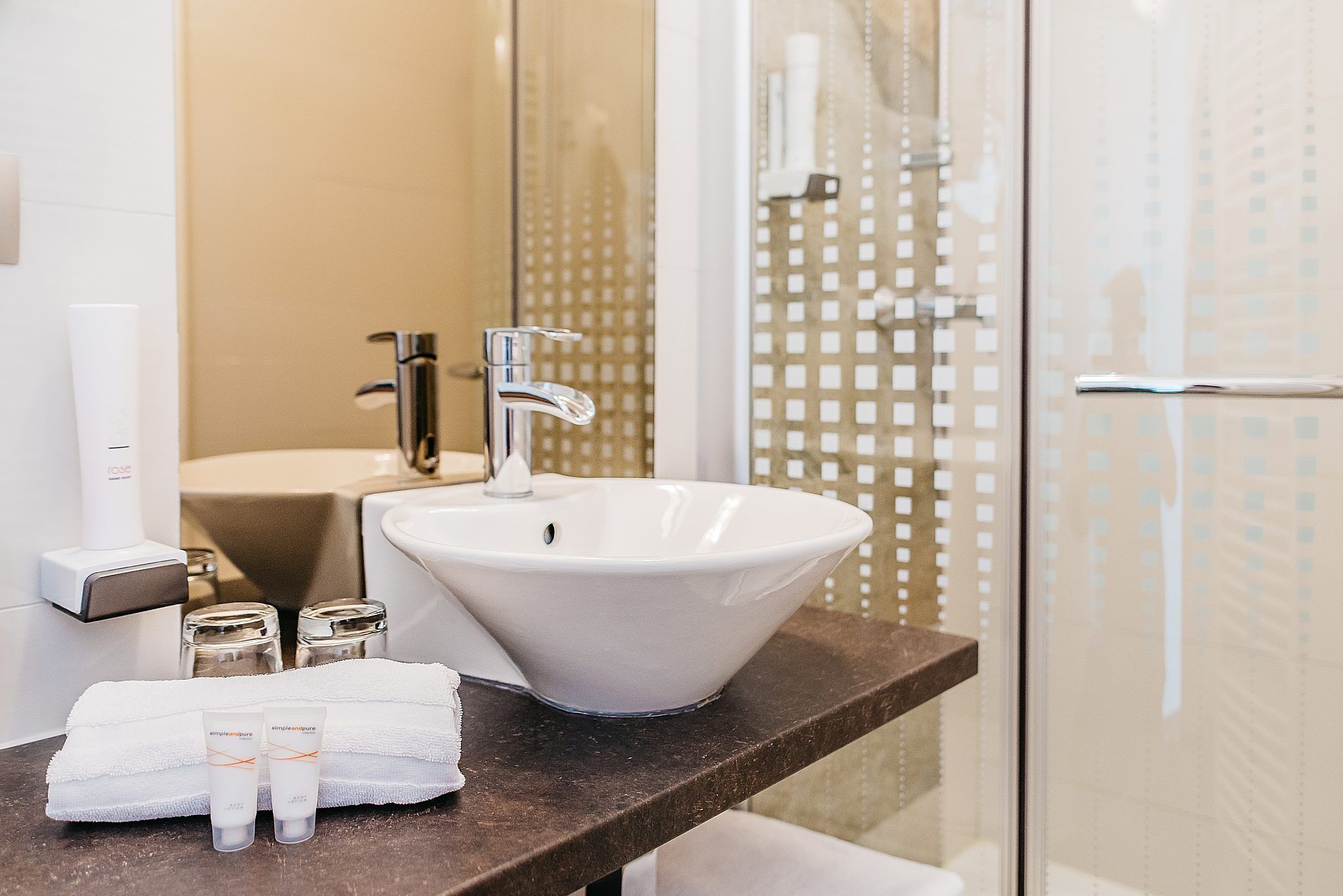 A bathroom with a white sink, a mirror, and a glass shower enclosure.