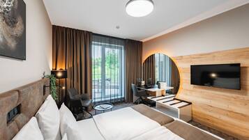 Ein modernes Hotelzimmer mit Bett, Schreibtisch, Stuhl, Fernseher und großen Fenstern.