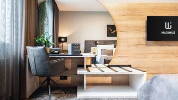 A modern hotel room with a desk, chair, bed, and a large mirror.