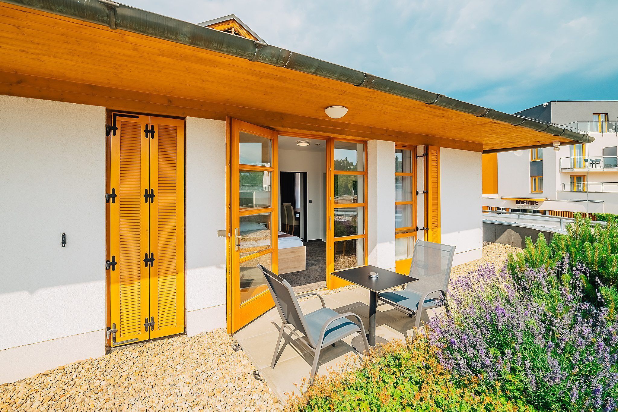 A modern building with a wooden roof, large glass doors, and a patio area with a table and chairs.