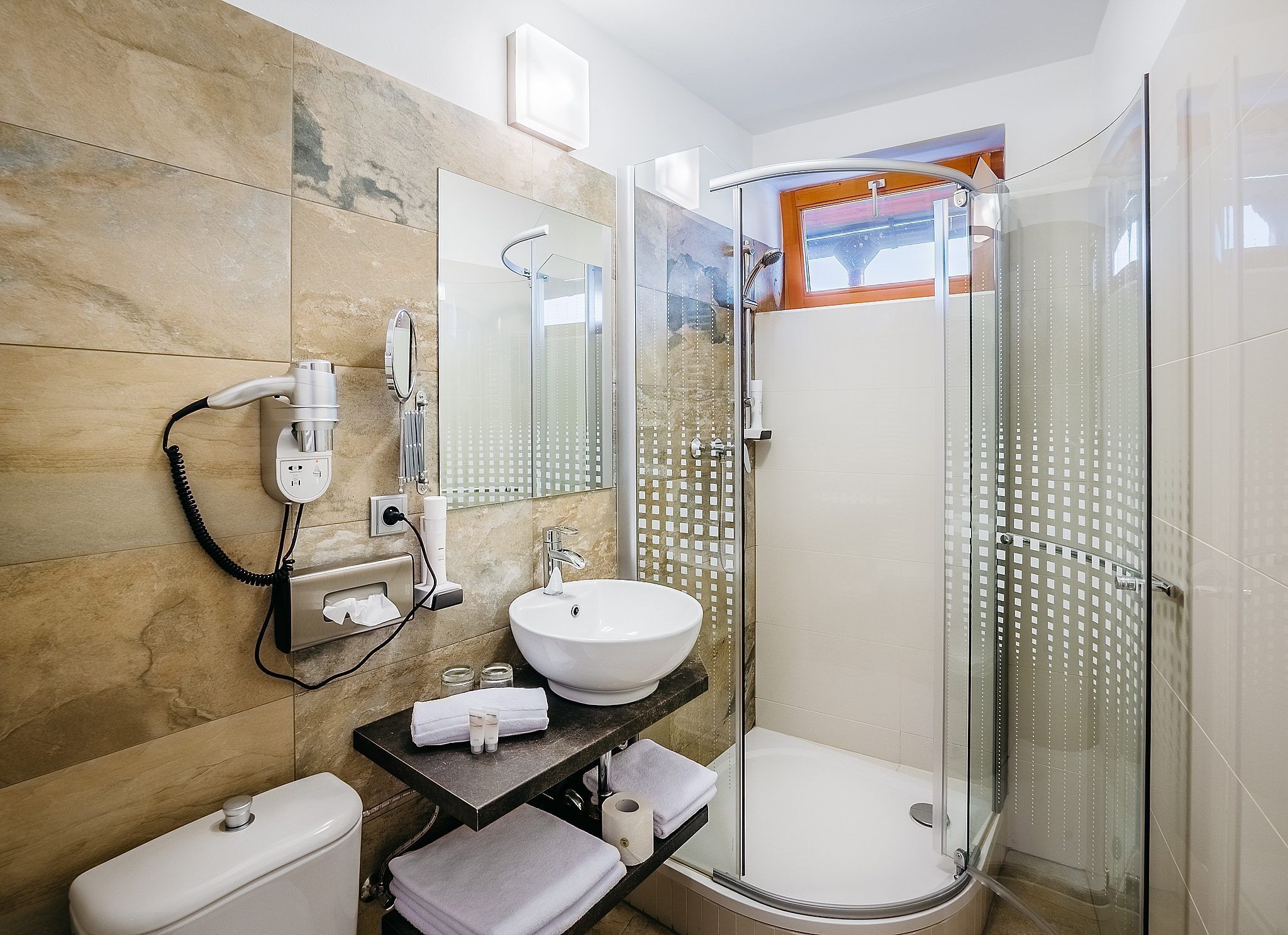 A modern bathroom with a glass-enclosed shower, a white sink, and a toilet.