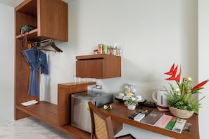 A compact kitchen with a built-in refrigerator, a wooden cabinet, and a dining table with a kettle and remote controls. - Secret Cliff Villa (Karon)