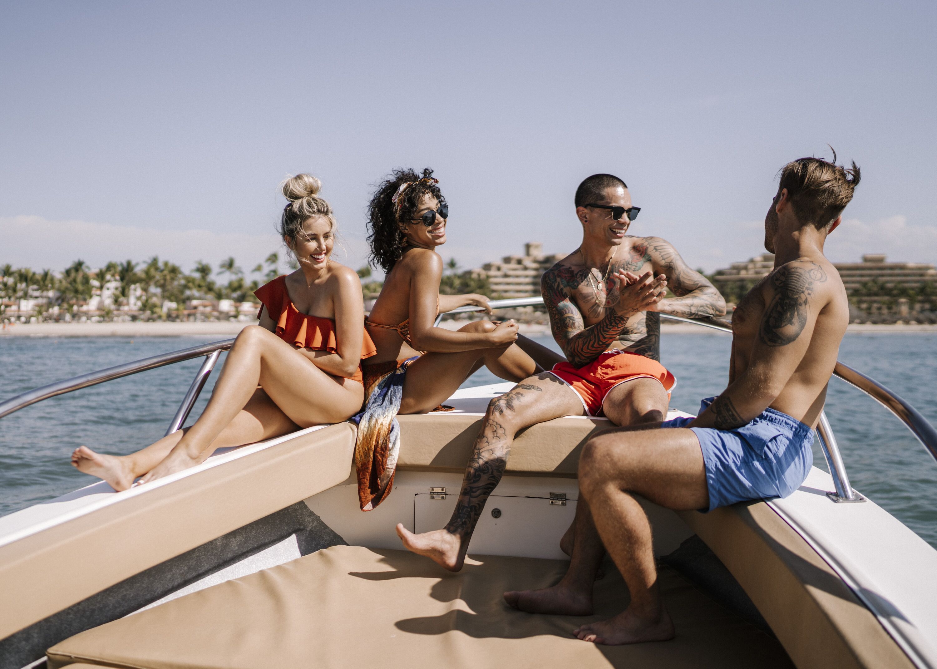 A group of people on a boat with a clear view of a beach and palm trees in the background.