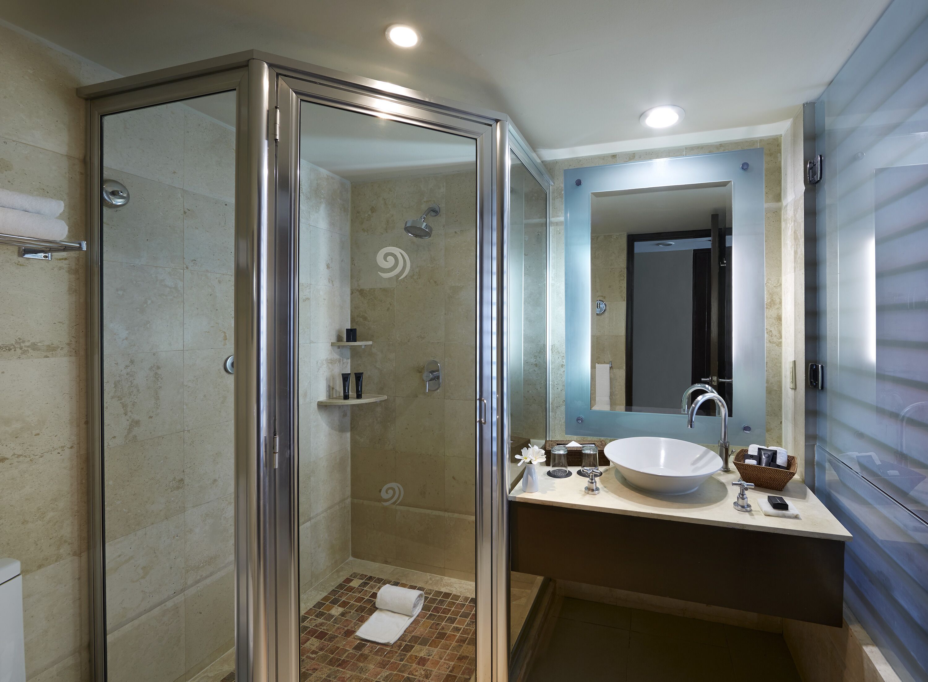 A modern bathroom with a glass-enclosed shower, a large mirror, and a sink with a vessel basin.