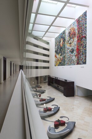 A modern interior with a long corridor, a large abstract art piece on the wall, and a seating area with unique furniture.