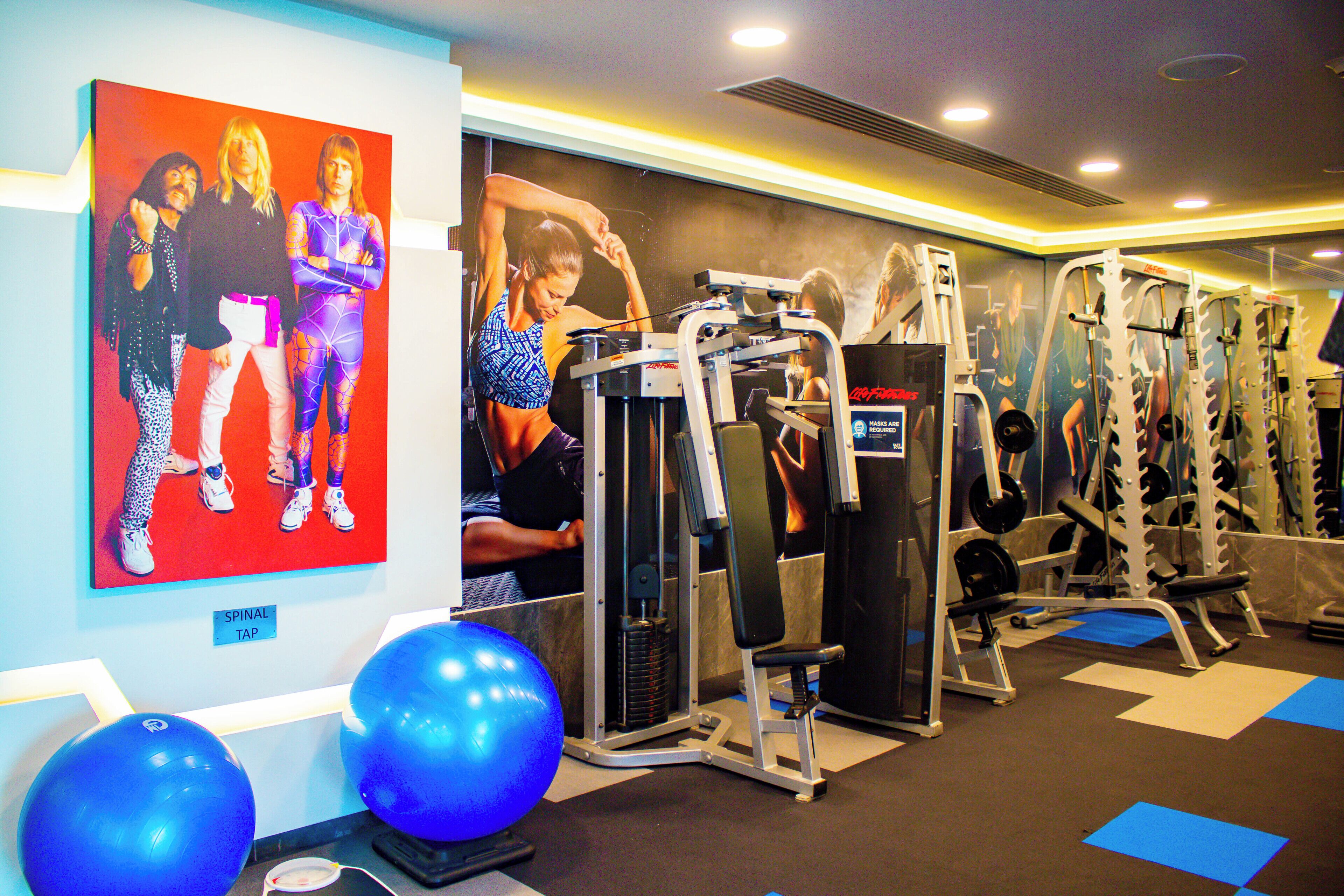 A gym with exercise equipment, blue exercise balls, and motivational posters on the walls.