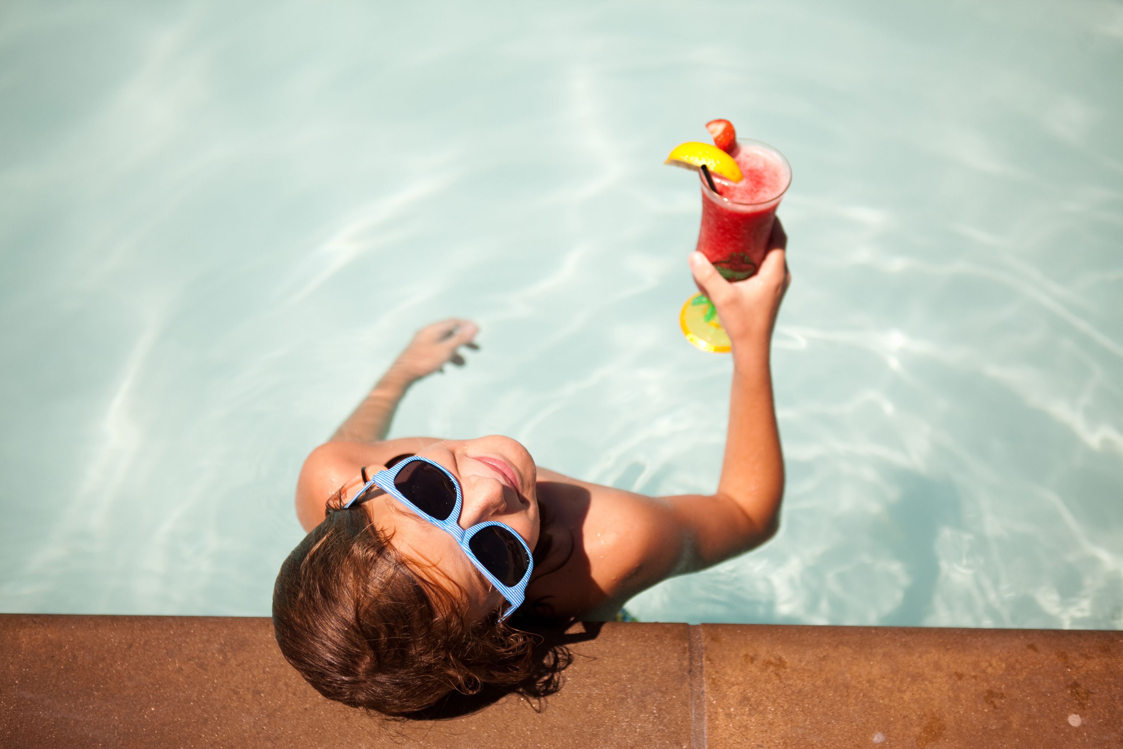 A person relaxing by a pool with a drink.