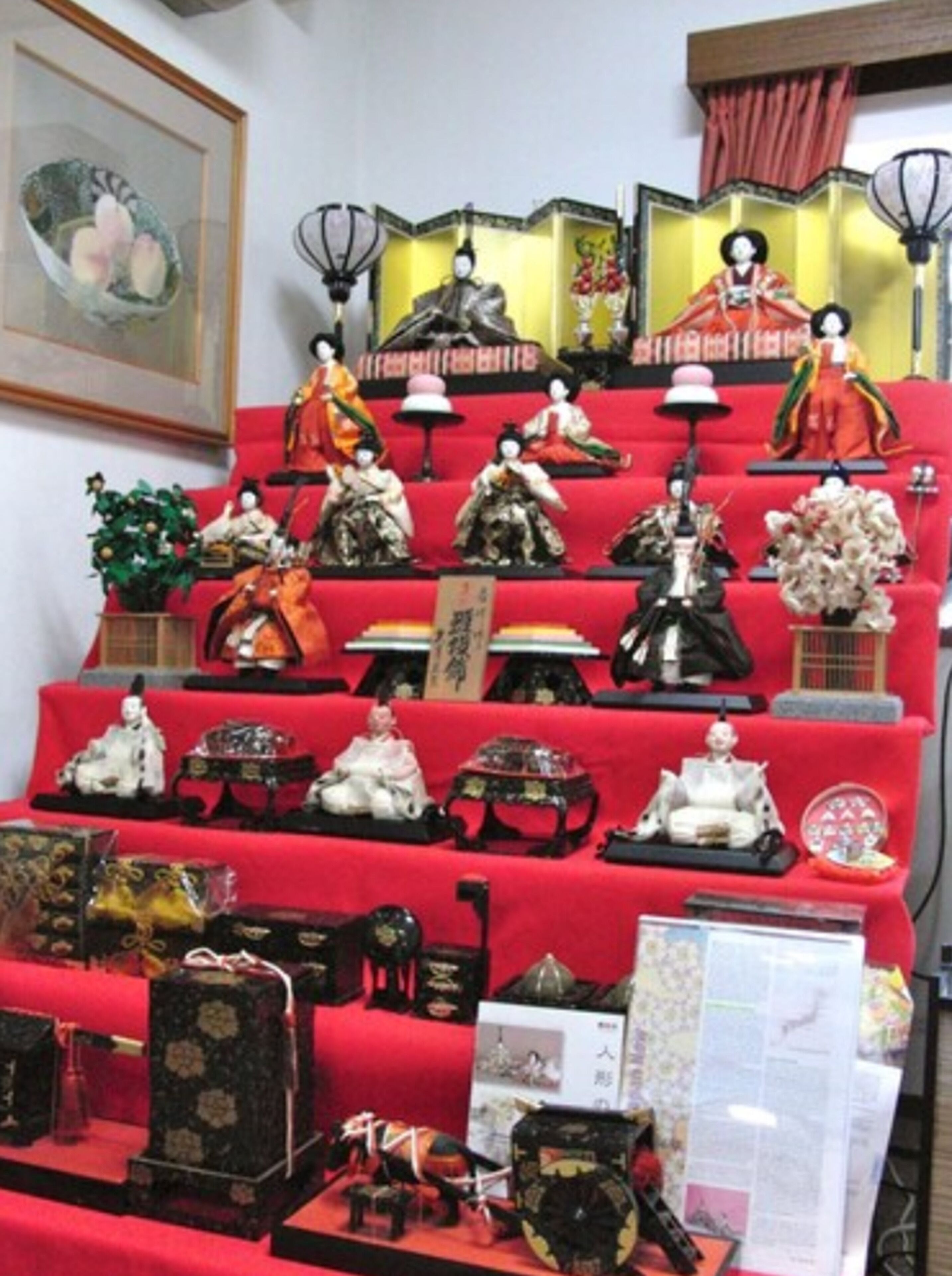 A display of traditional Japanese dolls and artifacts on a red carpeted staircase.