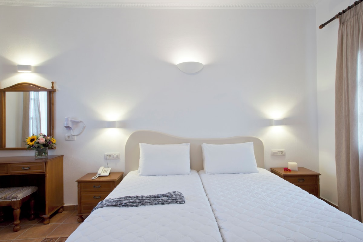 A hotel room with two beds, a wooden dresser, a mirror, and bedside lamps.