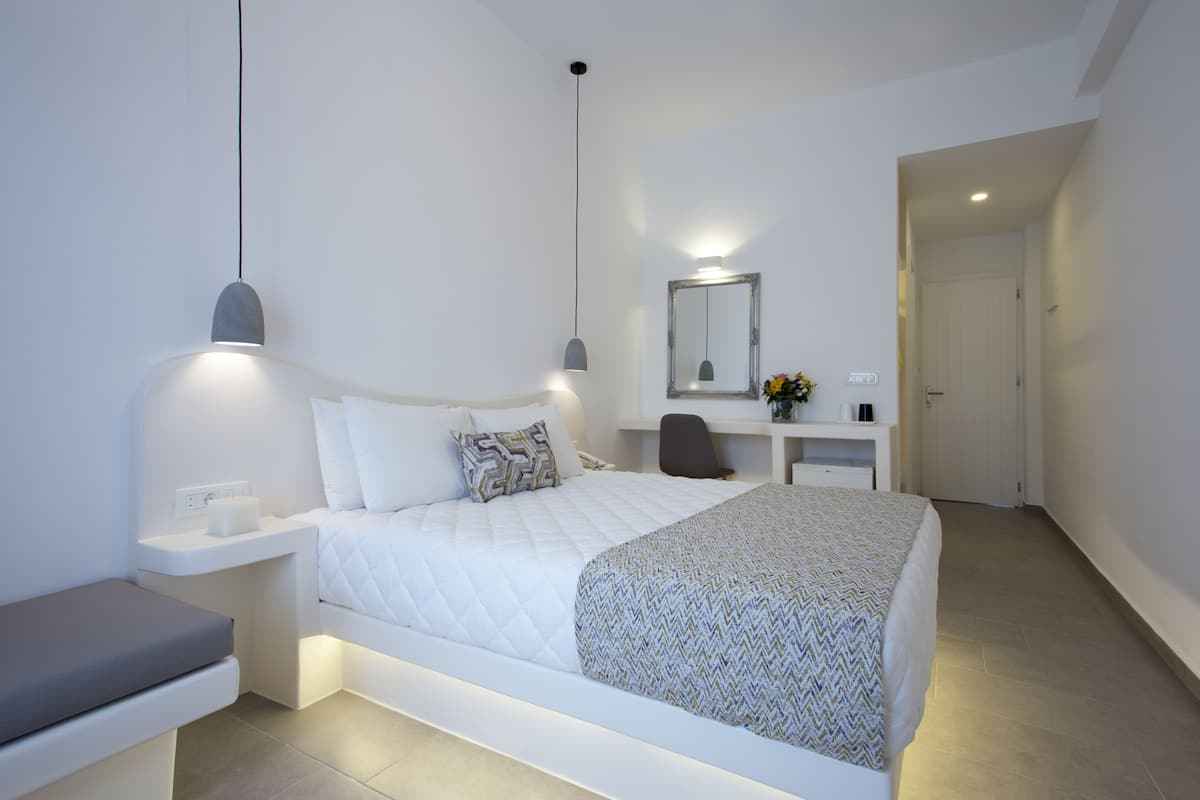 A modern bedroom with a bed, bedside tables, a desk, and a mirror.