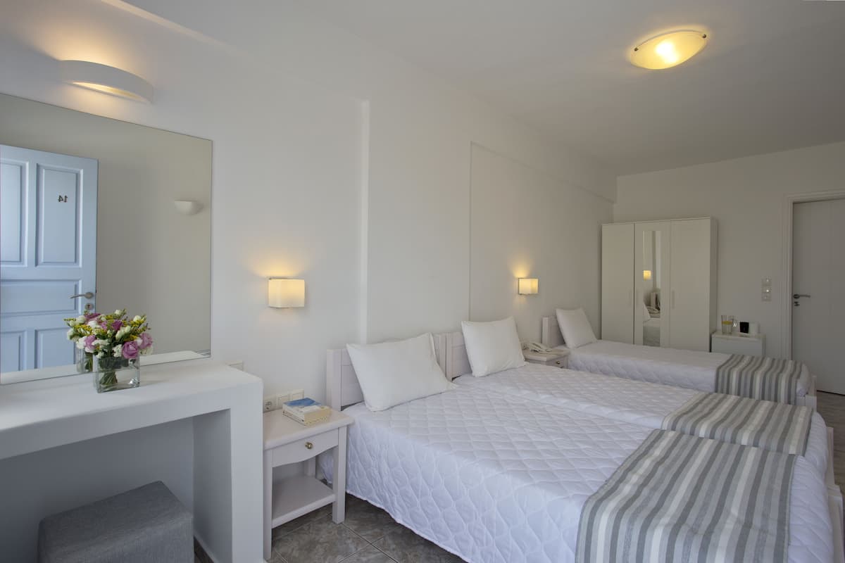 A hotel room with two beds, a vanity with a mirror, and bedside lamps.