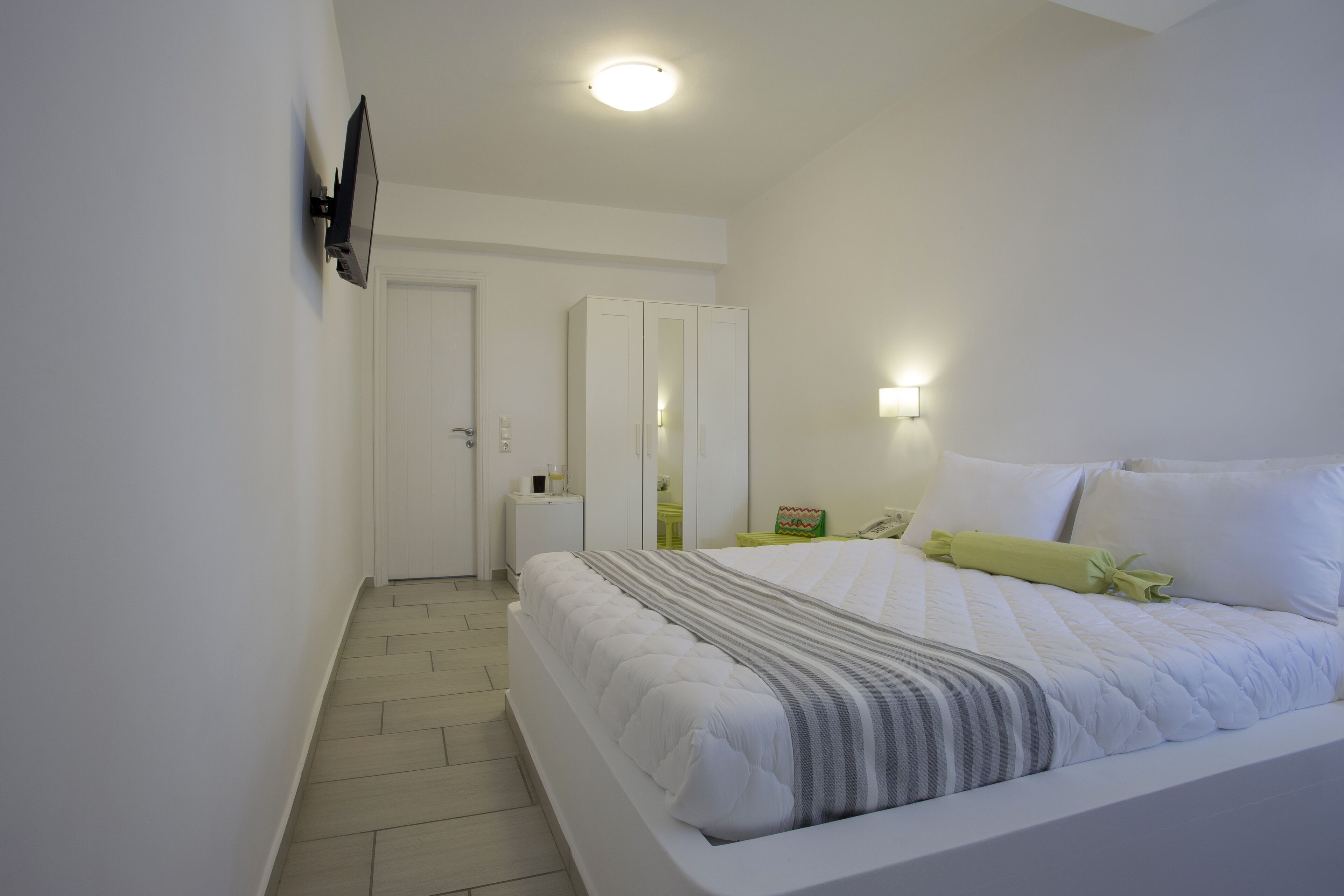 A bedroom with a bed, bedside table, and a wall-mounted TV.