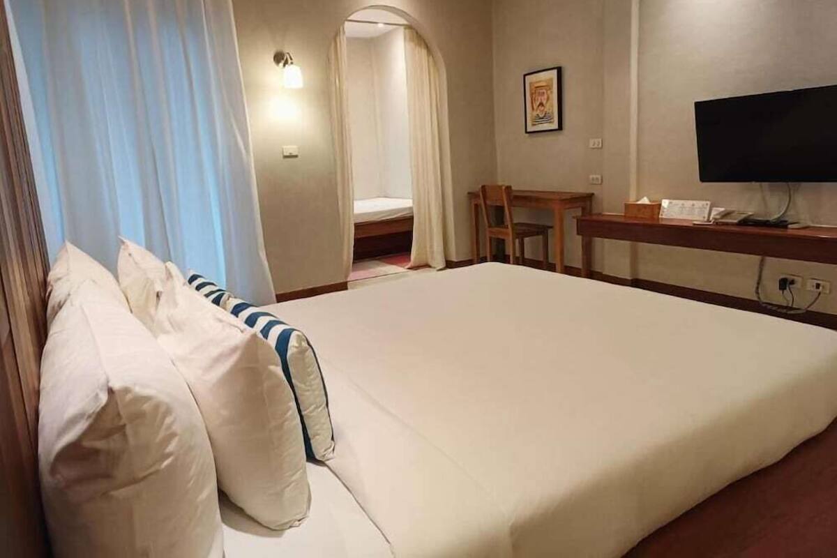 Ein Hotelzimmer mit einem Bett, einem Schreibtisch, einem Stuhl, einem Fernseher und einer Tür zu einem Badezimmer.
