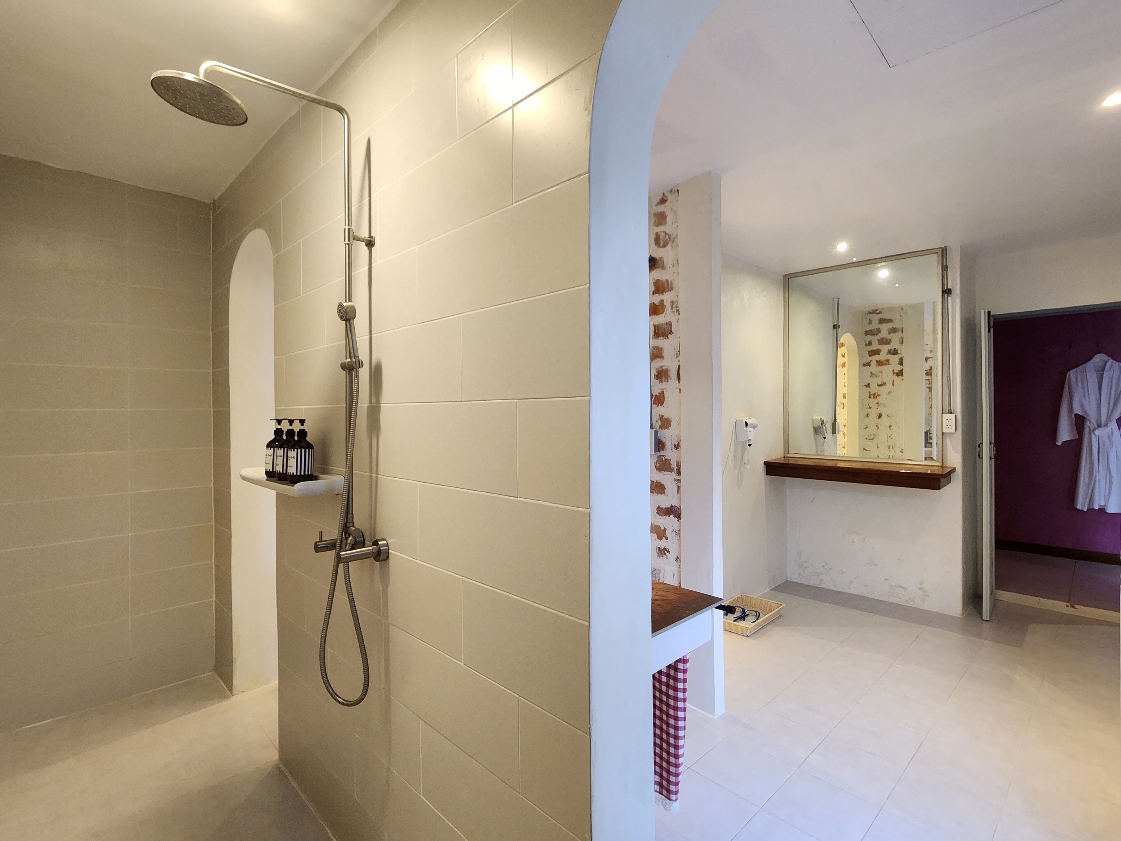 A modern bathroom with a shower, a vanity with a mirror, and a robe hanging on the wall.