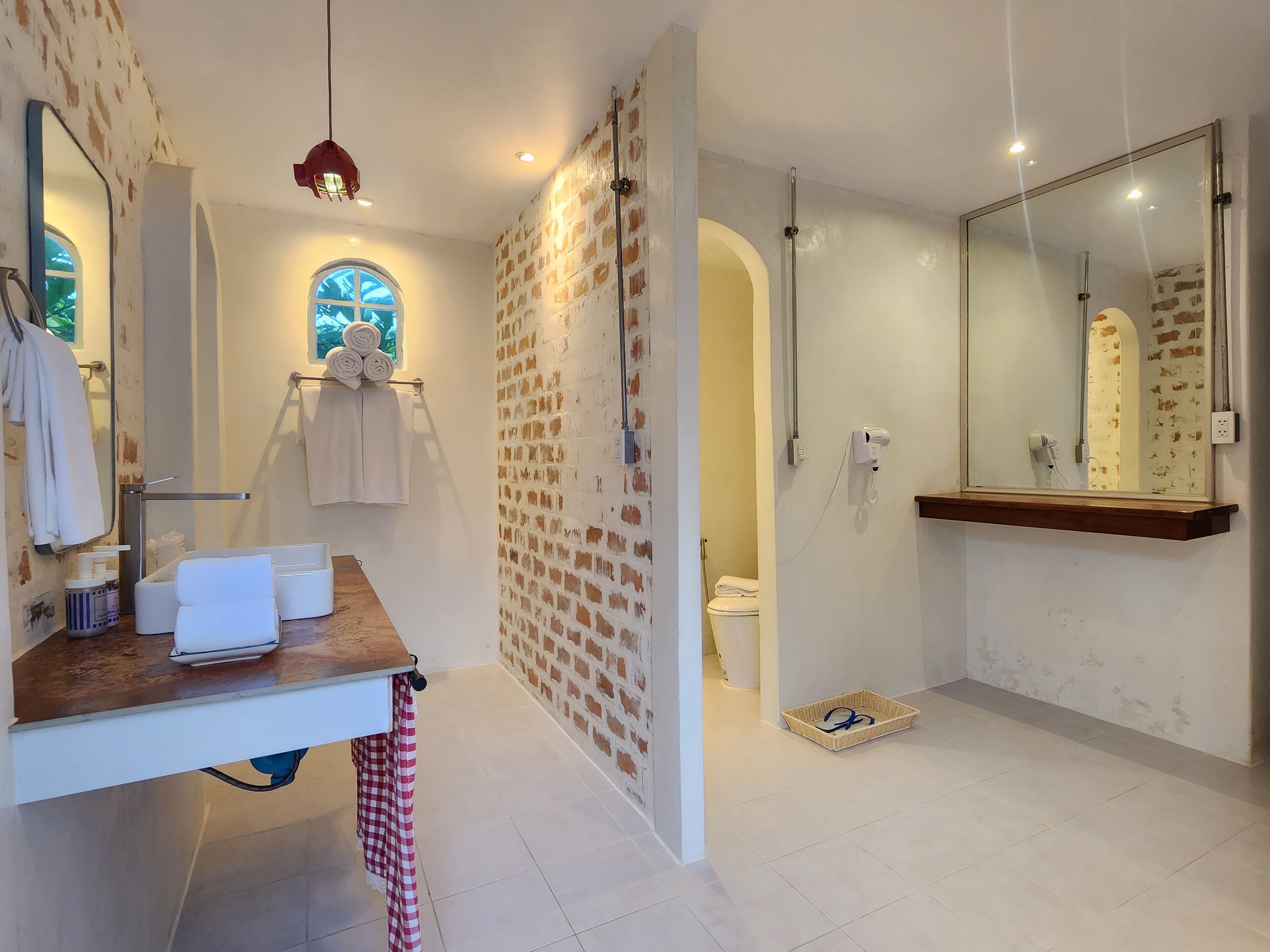 Un baño con tocador de madera, un espejo grande, toallero y zona de ducha.