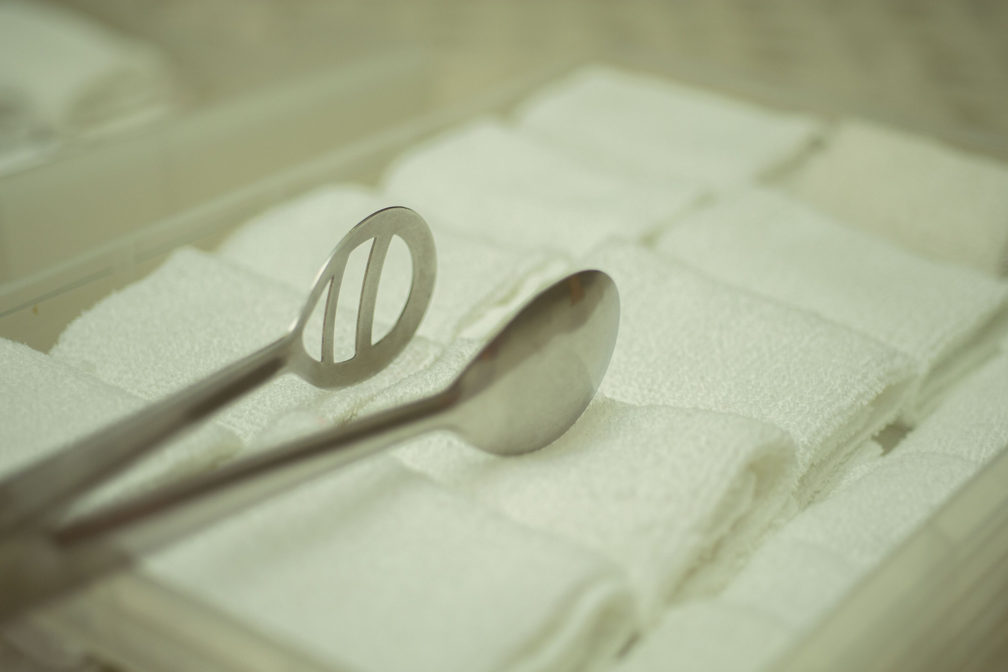 A spoon and a fork on a white textured surface.