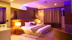 A modern hotel room with a large bed, bedside tables, a desk, and a chair. - SG Premium Resort (Arusha)