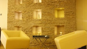 A modern room with a stone wall, two yellow armchairs, and a small table with a lamp. - SG Premium Resort (Arusha)