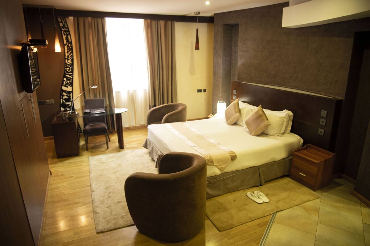 A hotel room with a bed, a desk, a chair, and a wardrobe.
