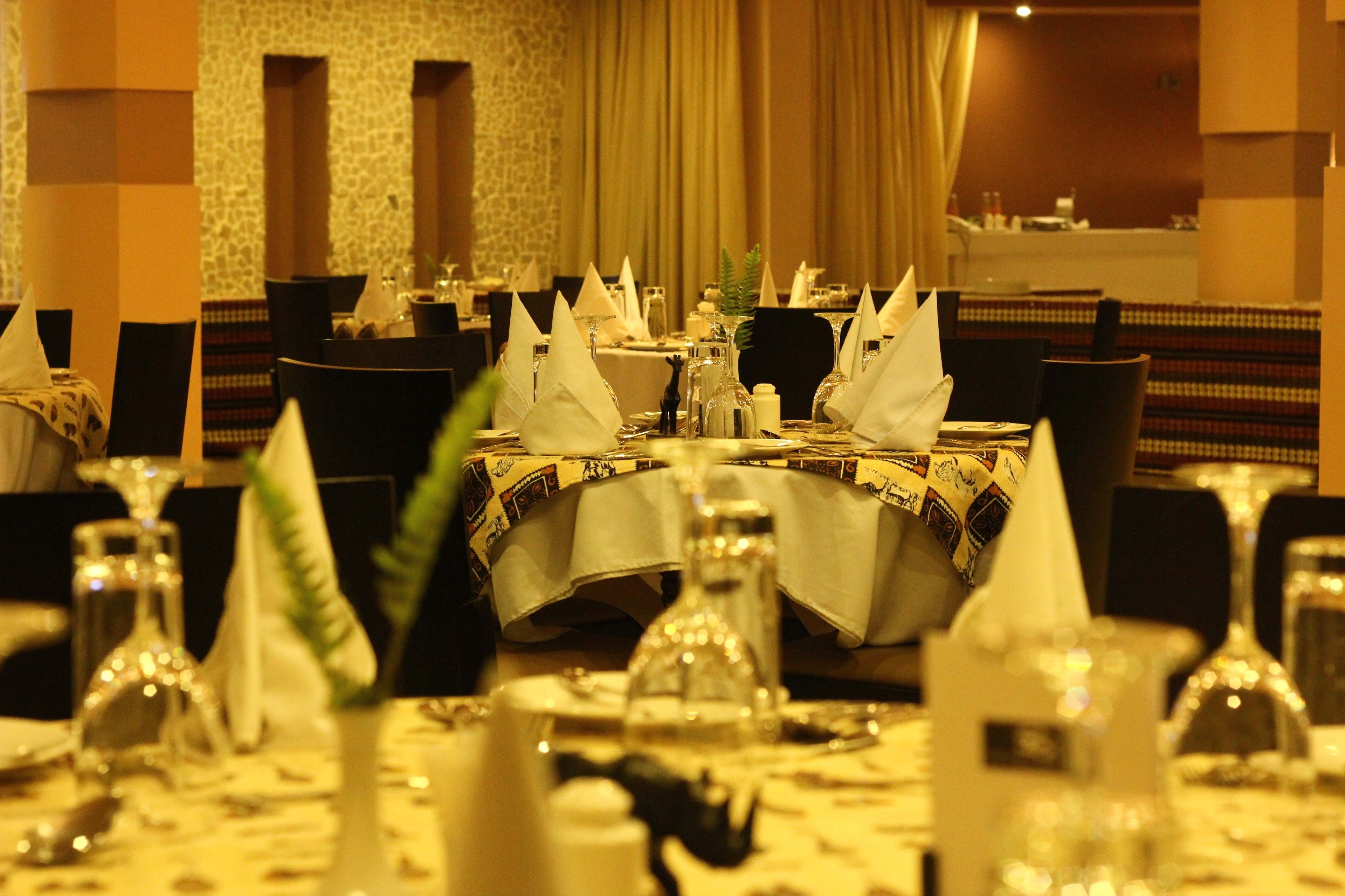 A dining area with tables set for a meal, featuring white tablecloths, napkins, and glassware.