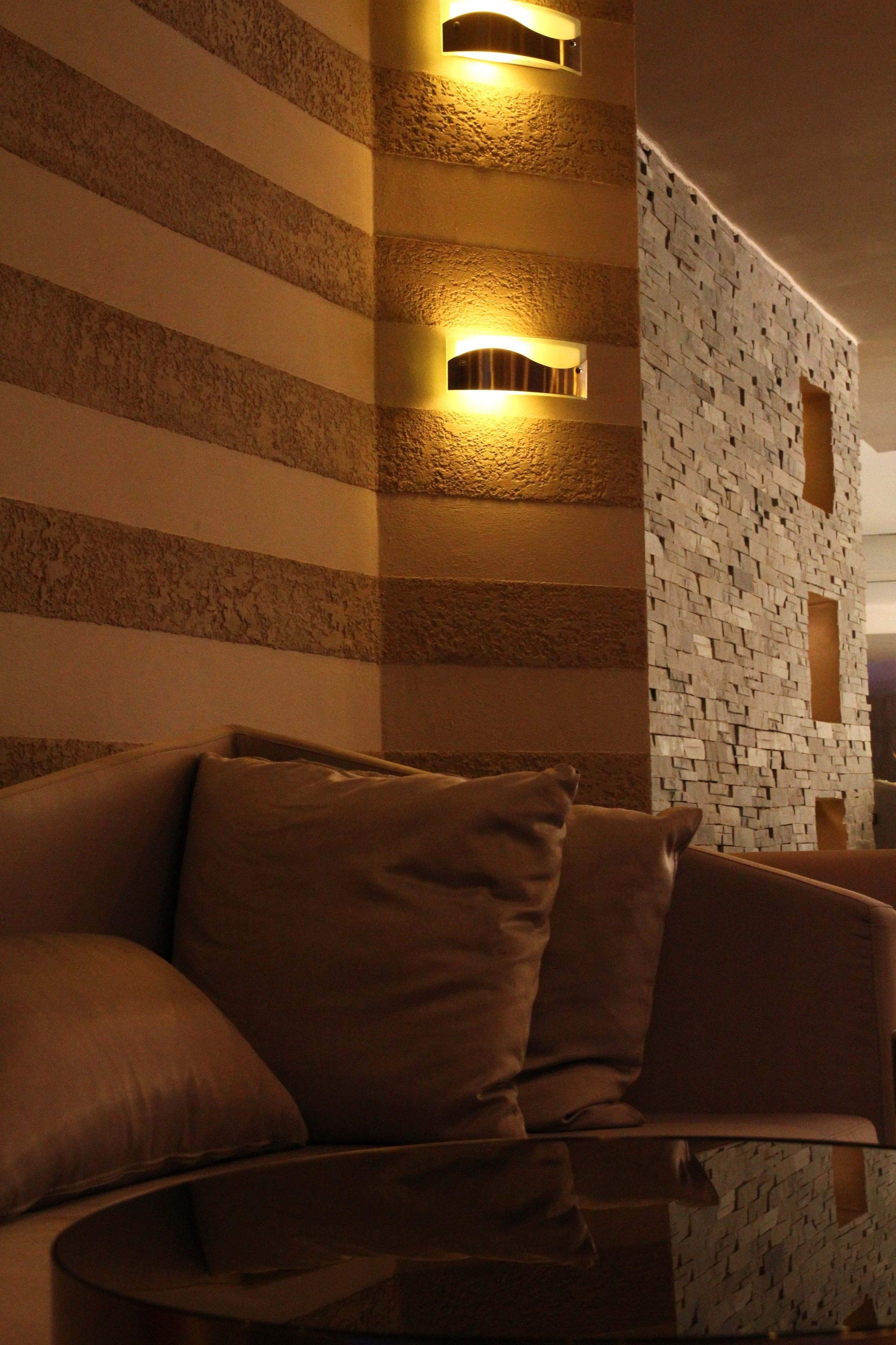 Een moderne woonkamer met een gestreept muur, een textuurrijk muur met mozaïekpatroon, en een bruine bank.