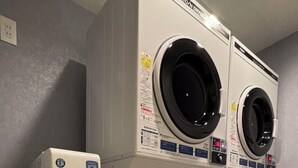 Un cuarto de lavandería con dos lavadoras de carga frontal, un secador apilado y un dispensador de hielo.