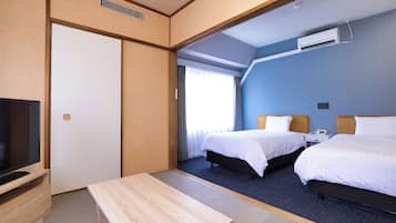 Una habitación de hotel con cama, mesita de noche, televisor y ventana con cortinas.