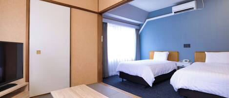 A hotel room with a bed, bedside table, TV, and a window with curtains.