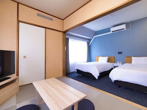 Una habitación de hotel con cama, mesita de noche, televisor y ventana con cortinas.