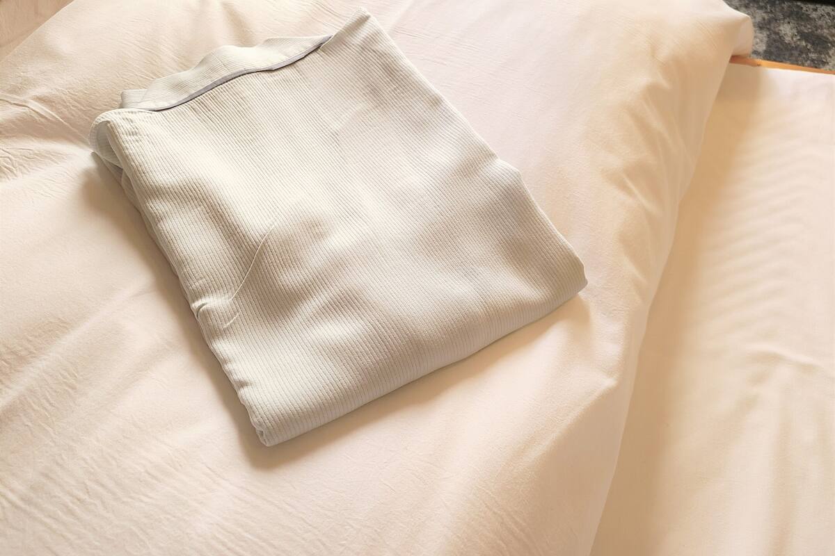 Un almohadón blanco, bien doblado, sobre una cama con cabecera de madera.