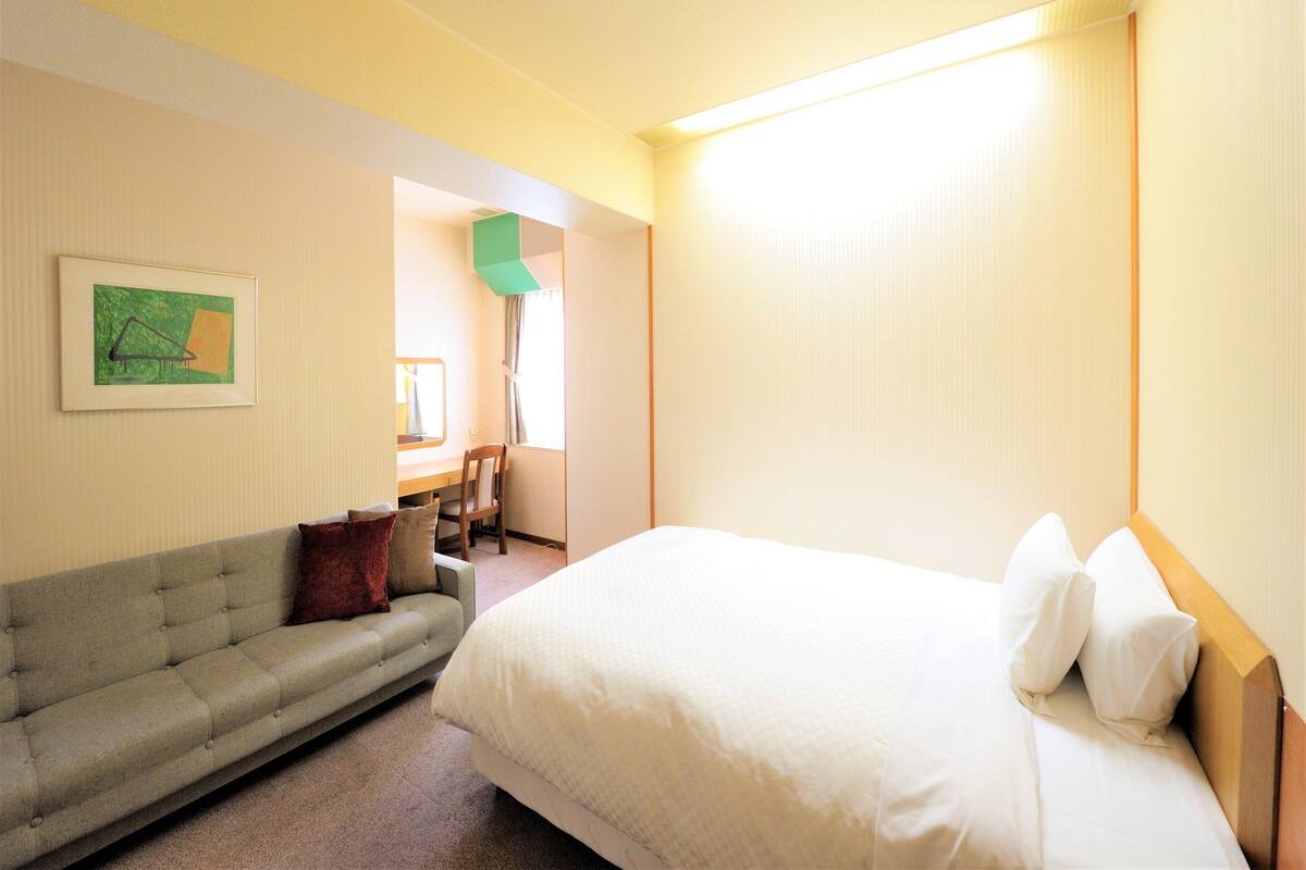 Habitación de hotel con cama, sofá, escritorio y un cuadro en la pared.