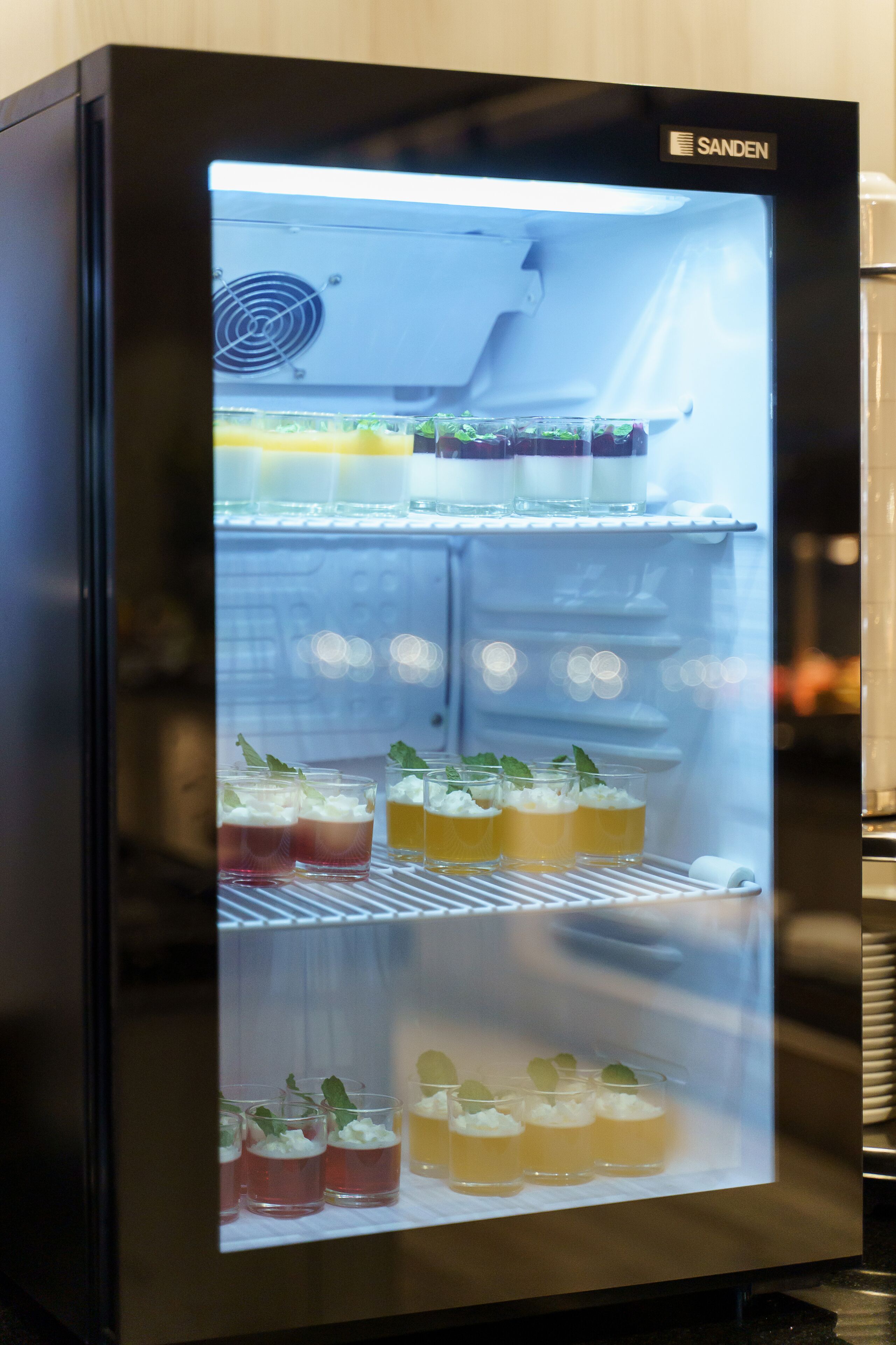 A refrigerator with multiple shelves containing various drinks and garnishes.