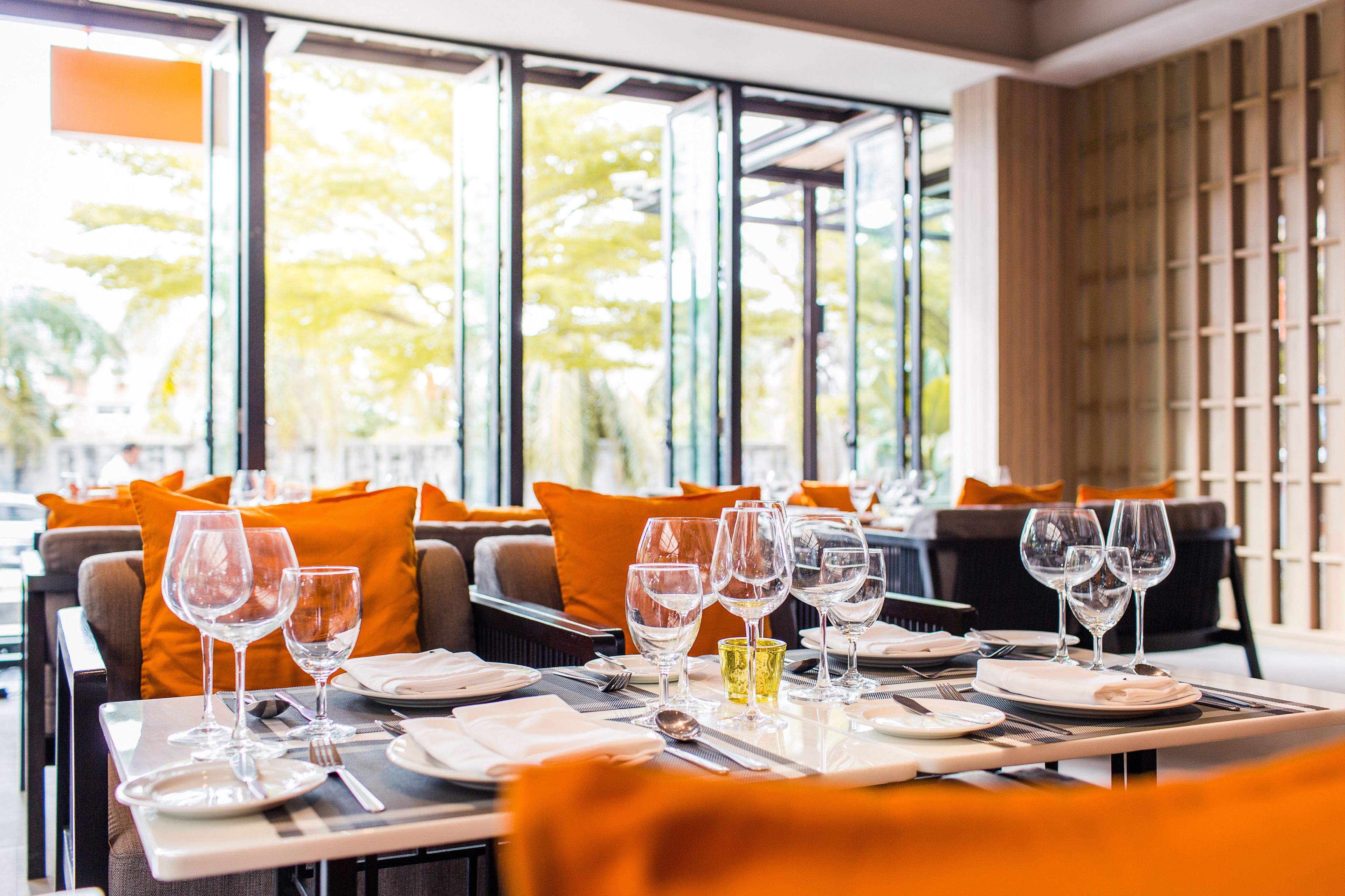 A restaurant setting with tables set for dining, featuring clear glassware and cutlery.