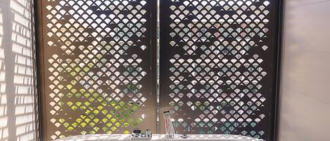 A spa area with a large bathtub filled with water and rose petals, a wooden ceiling, and a decorative screen.