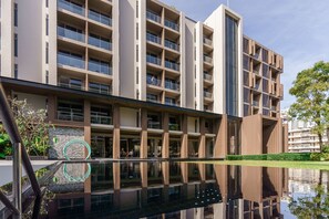 A modern multi-story hotel with a reflective pool in front. - Fifth Jomtien Pattaya (Pattaya)
