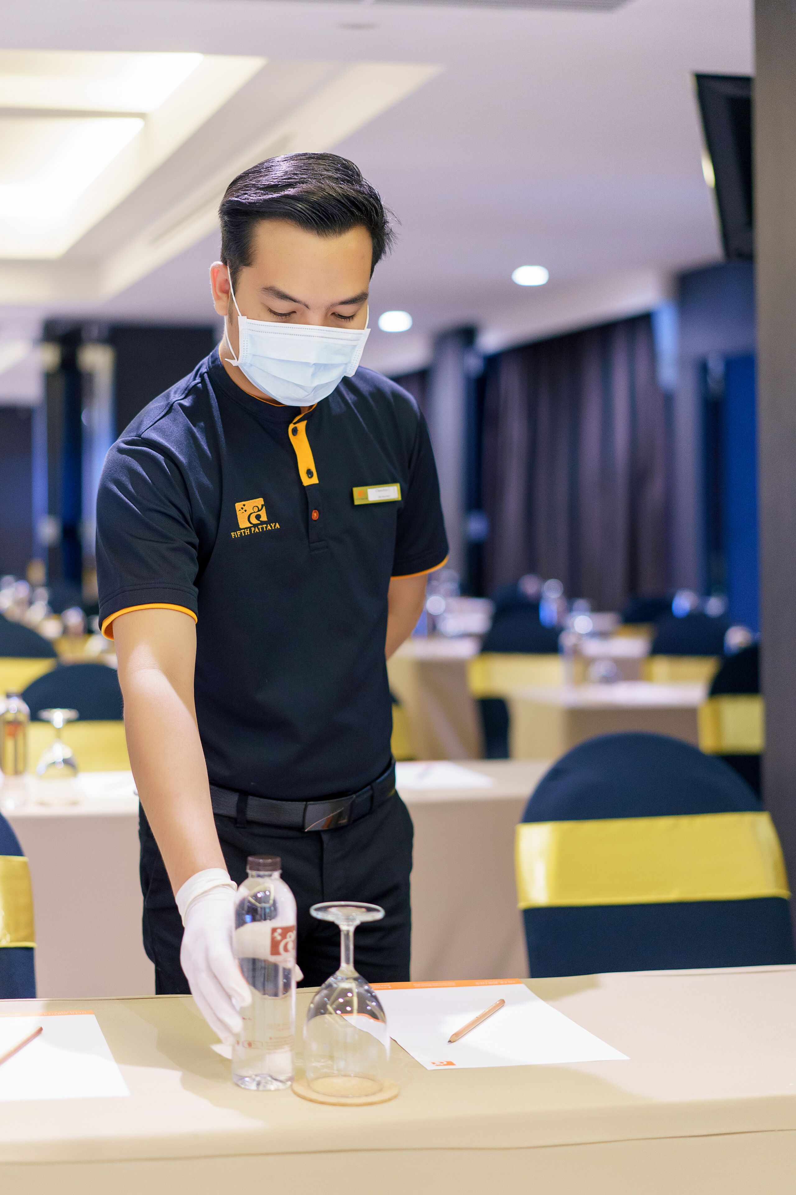 Ein Hotelmitarbeiter arrangiert einen Tisch mit einer Flasche, einem Glas und einem Notizblock.