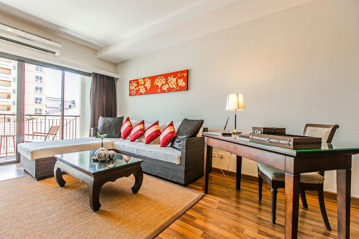 A modern living room with a sofa, coffee table, and a desk with a lamp.