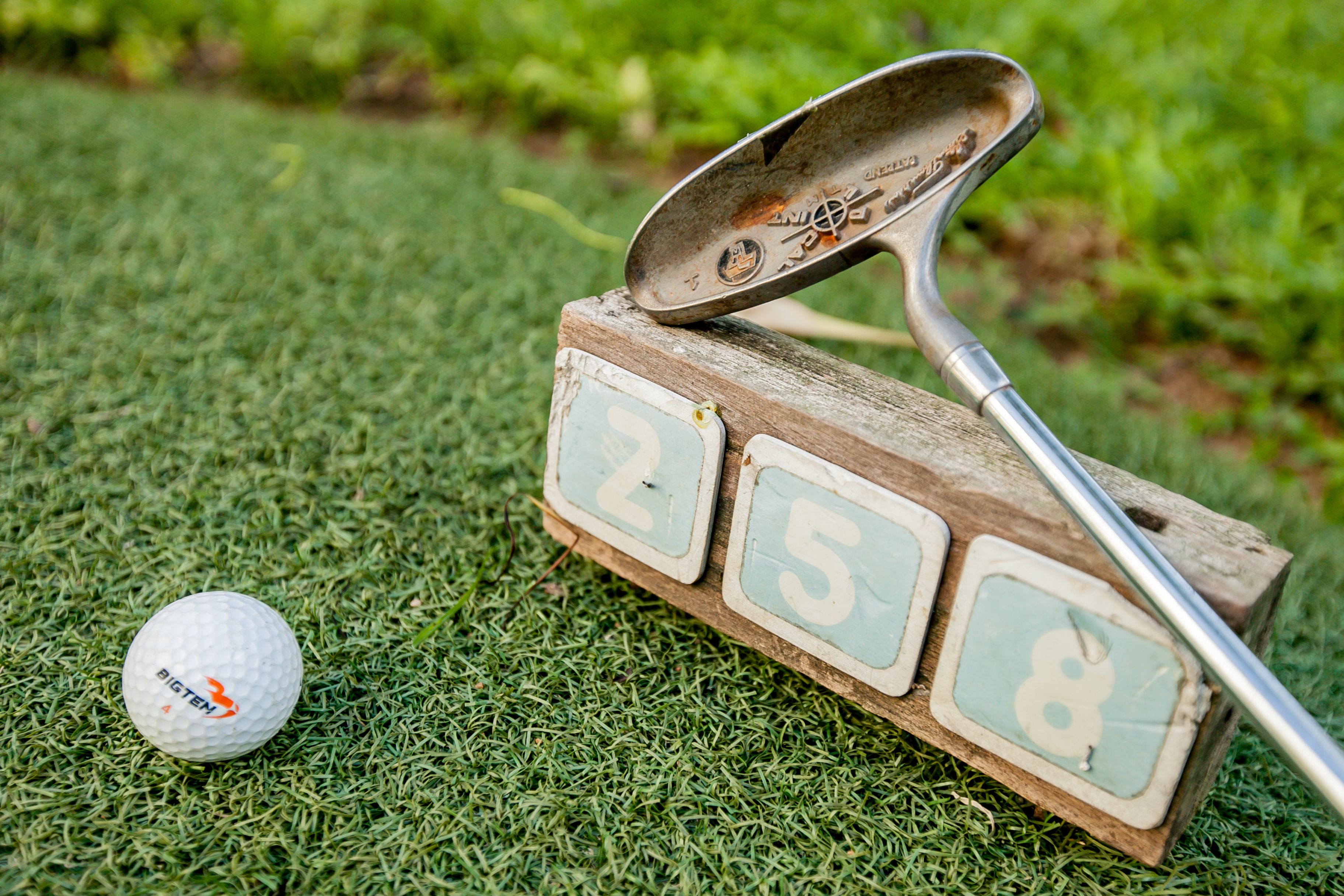 A golf ball and a putter on a wooden number board.