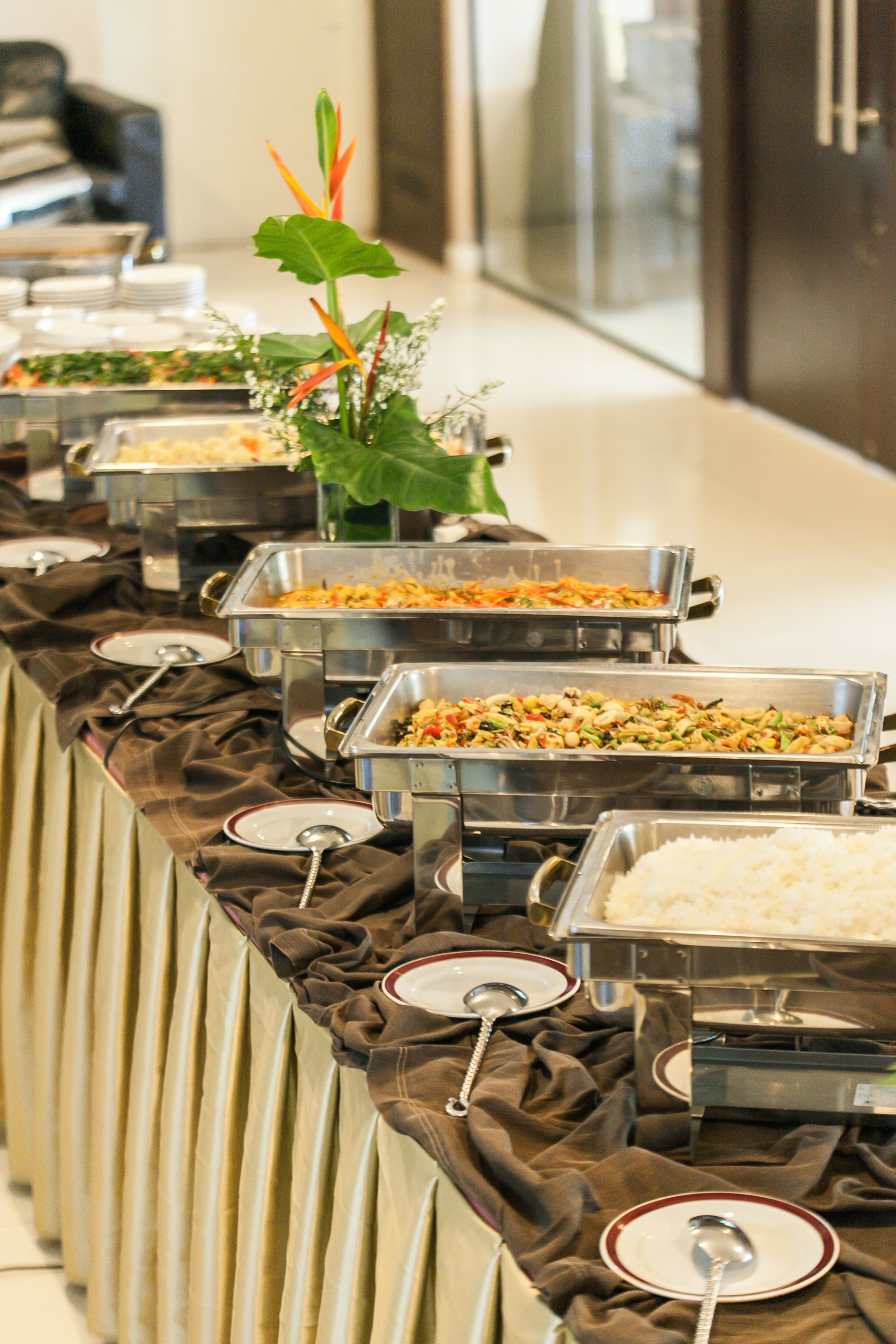 Una mesa de buffet con diversas opciones de comida y utensilios de servicio.