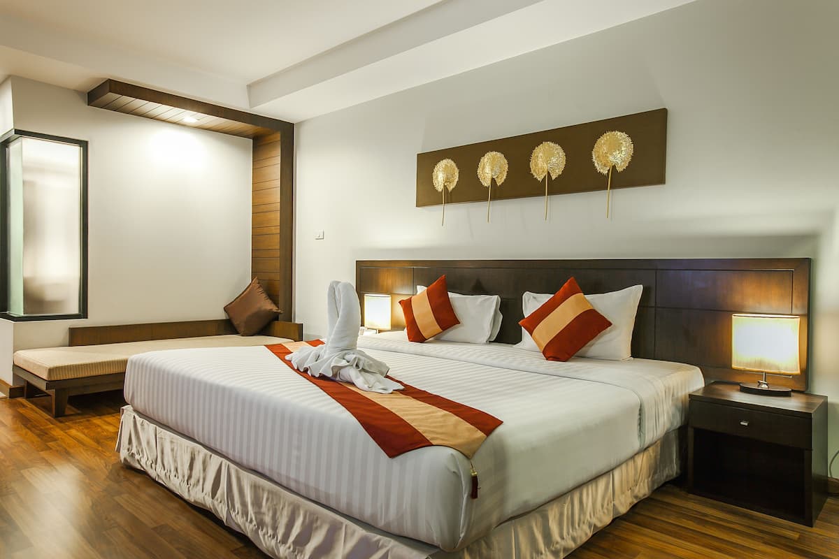 A hotel room with a large bed, two bedside tables, a bench, and a wall-mounted artwork.