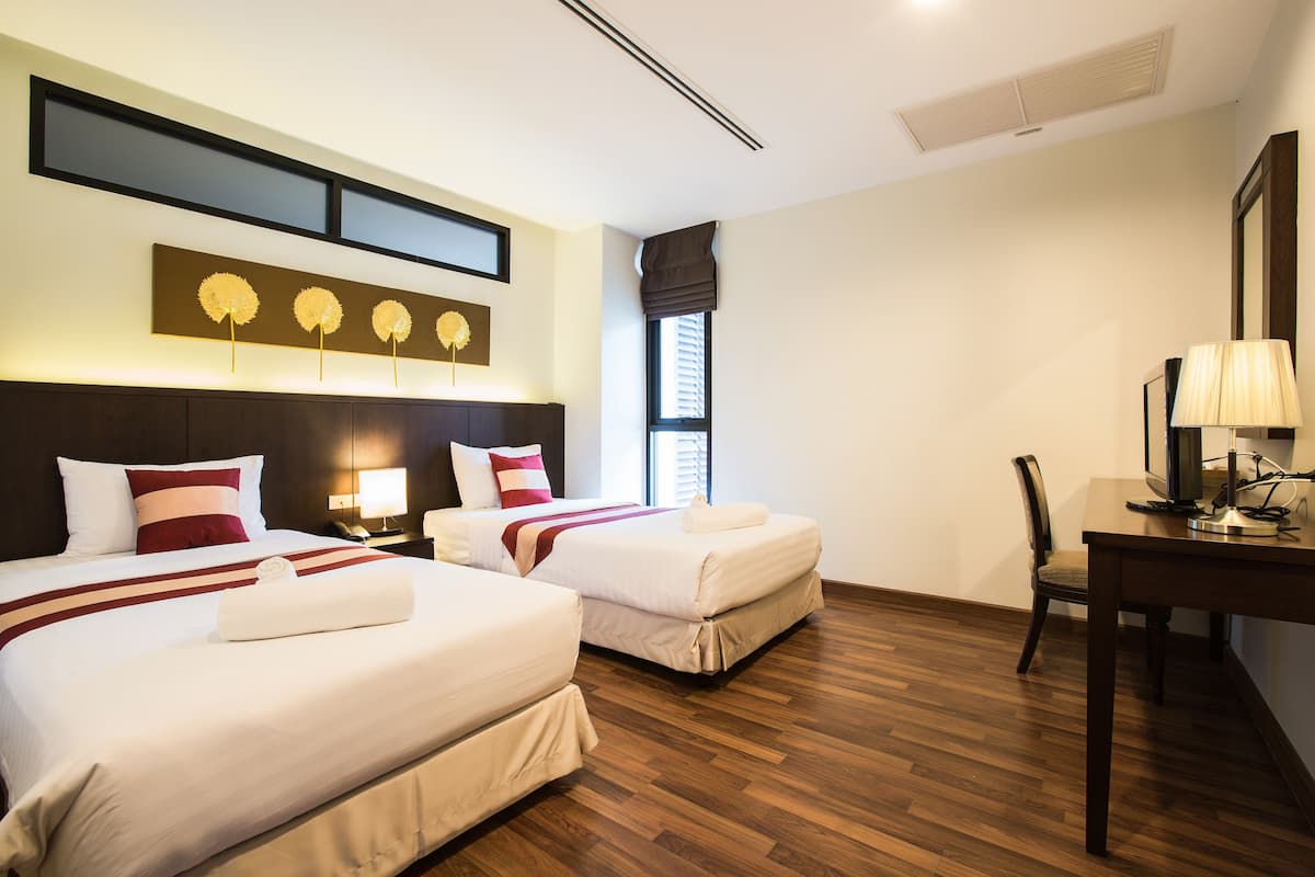A hotel room with two beds, a desk, and a chair.