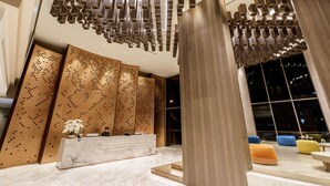 Uma área de recepção moderna com balcão de mármore, painéis de madeira nas paredes e um design de teto único.