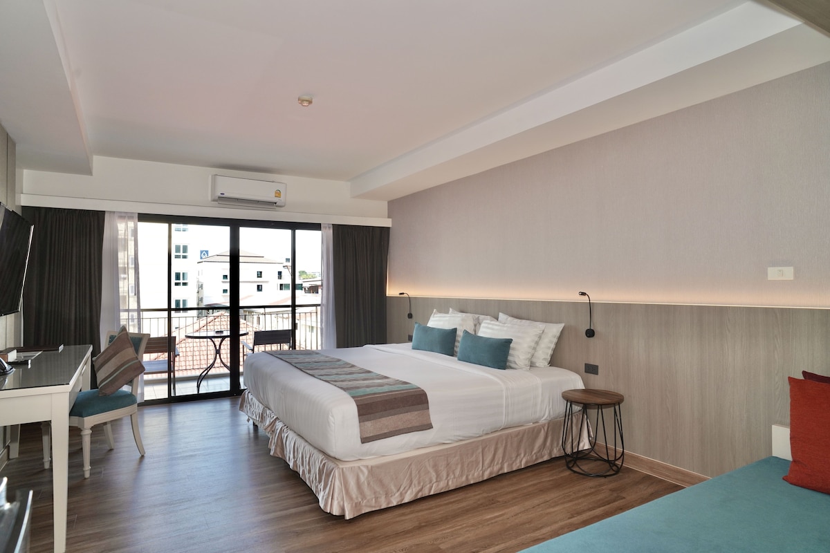 Ein Hotelzimmer mit Bett, Schreibtisch, Stuhl und Blick ins Freie.